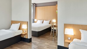 Ein Hotelzimmer mit zwei Betten, einem Schreibtisch und einem Stuhl.