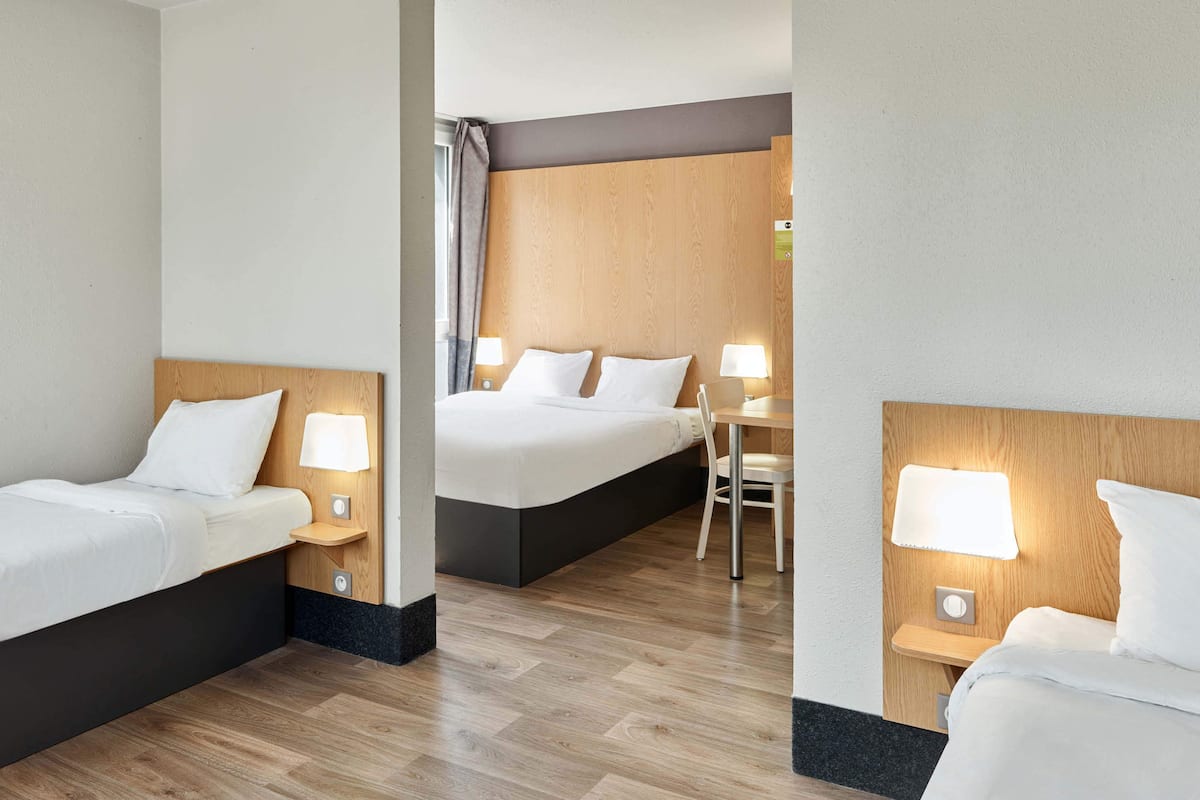 Ein Hotelzimmer mit zwei Betten, einem Schreibtisch und einem Stuhl.