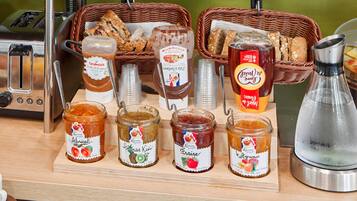 A breakfast buffet with various jams, bread, and a coffee machine.