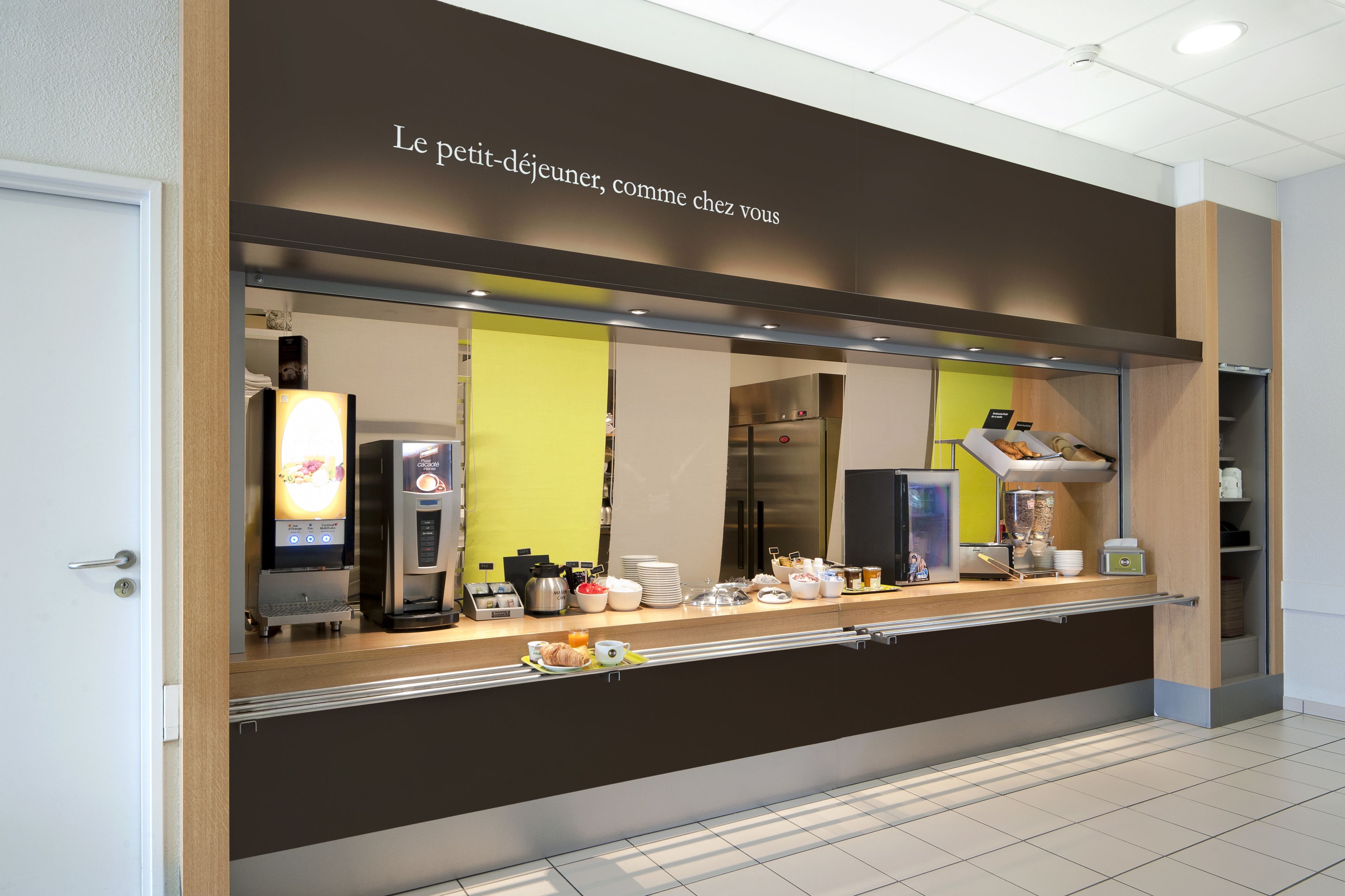 Una barra de desayuno con una cafetera, dispensador de té y diversas opciones de comida.