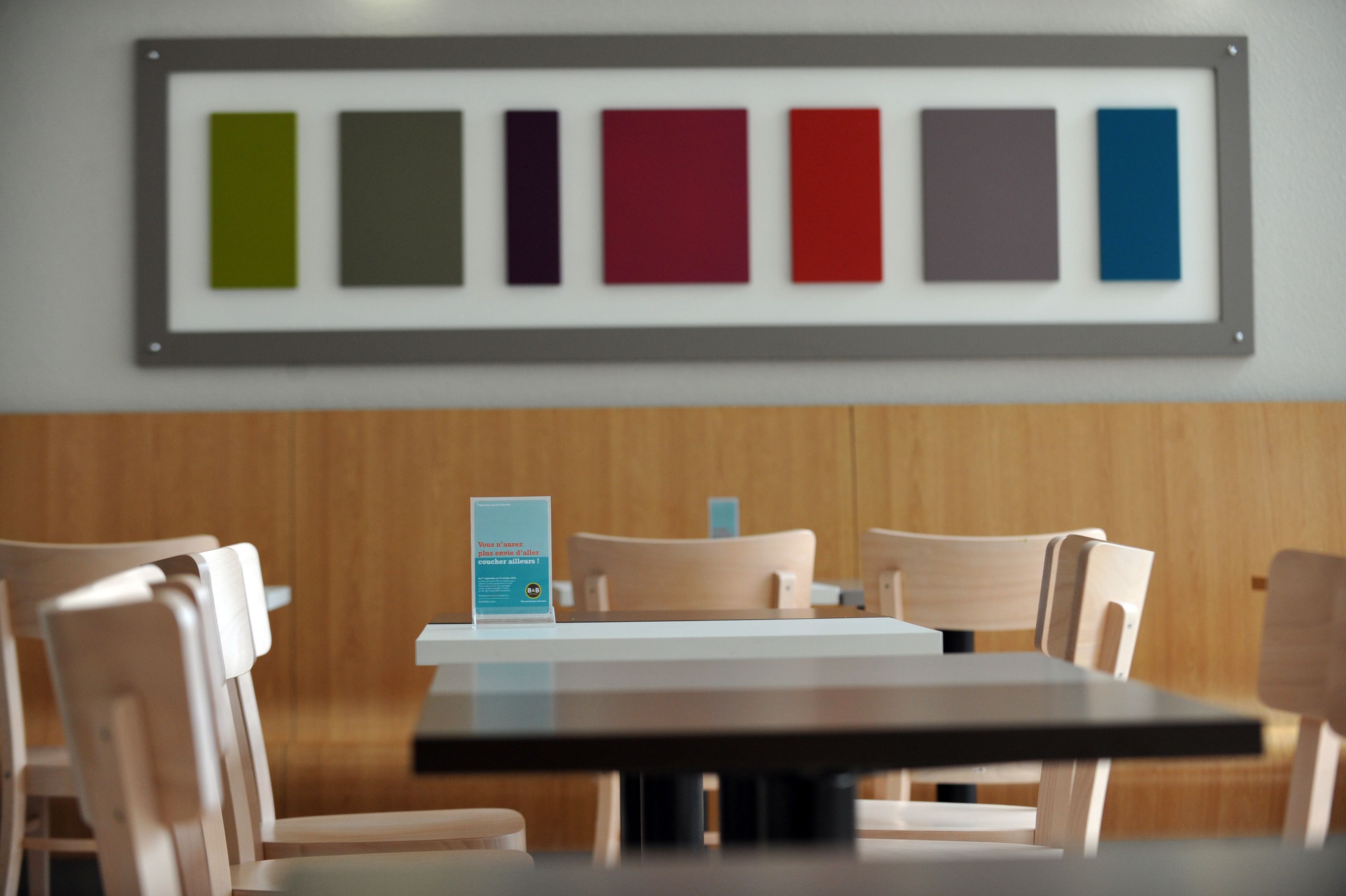 Un coin repas avec une table et des chaises, un échantillon de couleurs encadré accroché au mur et un présentoir à menus.