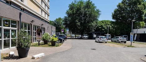 Un edificio con un letrero que dice "B&B Accueil" y un estacionamiento con coches.