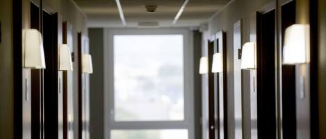 A hotel hallway with doors on both sides, each with a light fixture above.