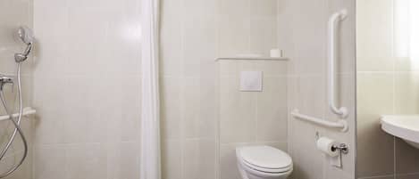 Baño con ducha, inodoro y barras de apoyo.