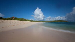 Una playa con cielos despejados y aguas tranquilas.