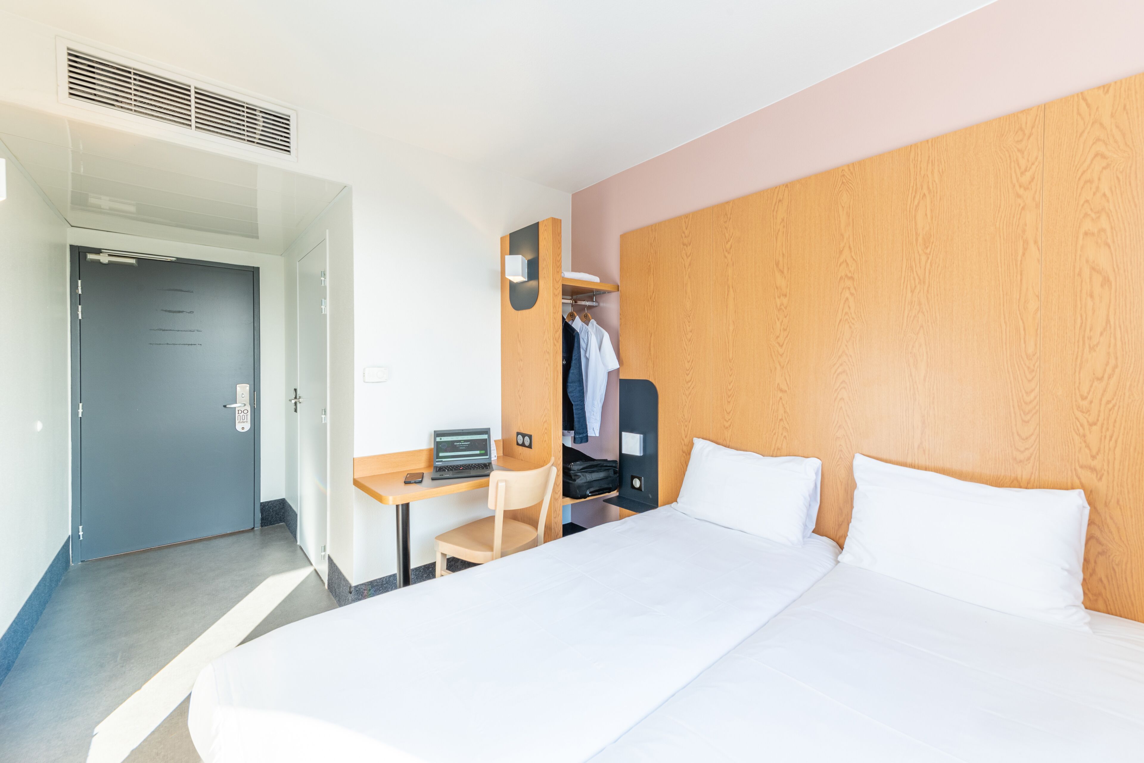 A hotel room with a bed, desk, chair, and wardrobe.