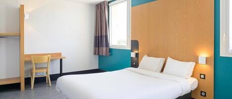 A hotel room with a bed, a desk, and a chair.