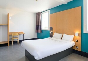 A hotel room with a bed, a desk, and a chair. - B&B HOTEL Lieusaint Carré Sénart (Lieusaint)