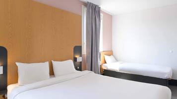 A hotel room with a large bed, a smaller bed, and a nightstand with a lamp.