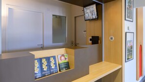Een receptiebalie met een flatscreen televisie, een ingelijst poster en informatief promotiemateriaal.