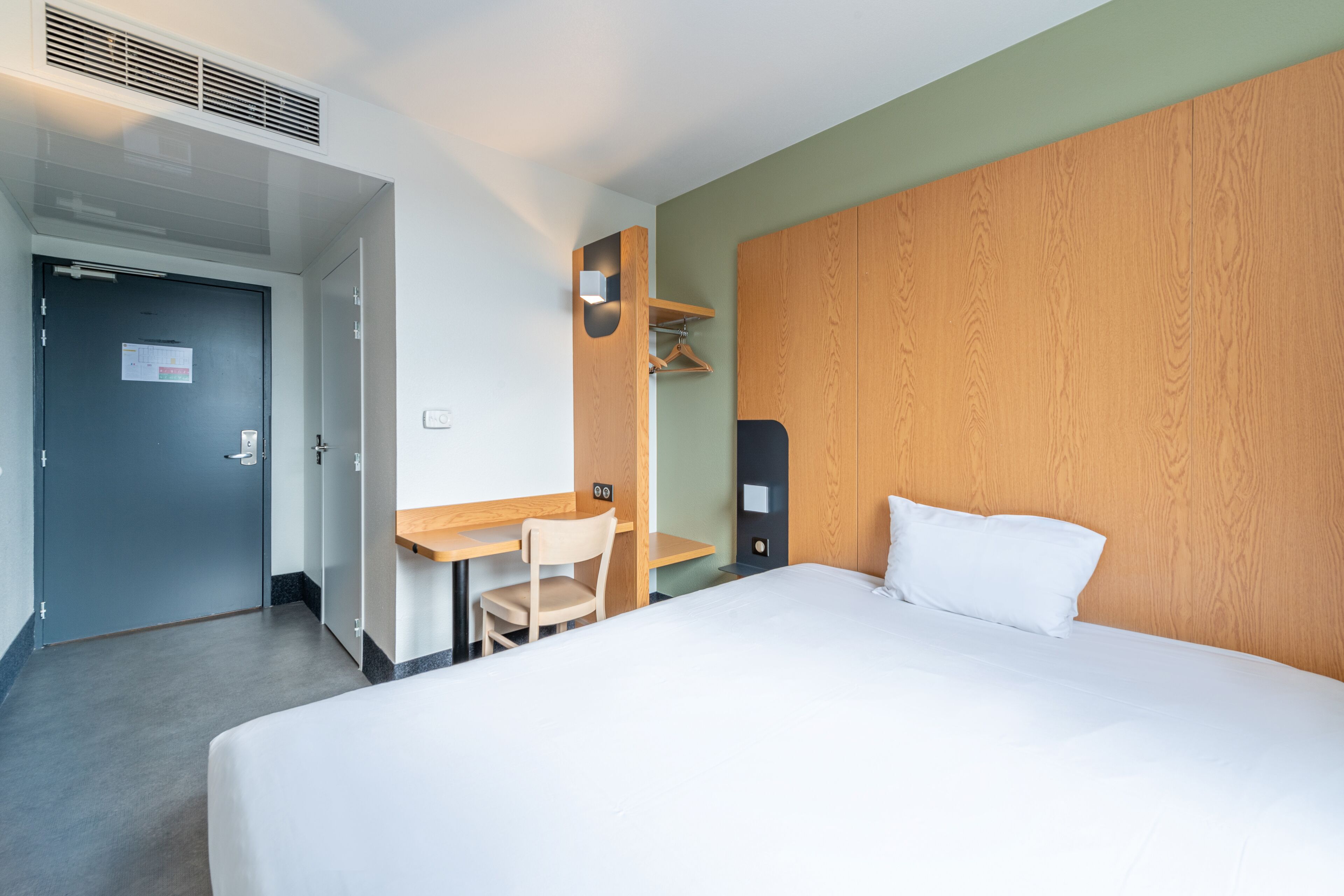 Una habitación de hotel con cama, escritorio, silla y armario.