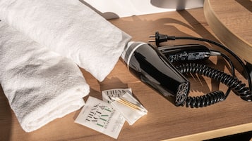 A neatly folded white towel, a black hairdryer, and a pamphlet on a wooden surface.