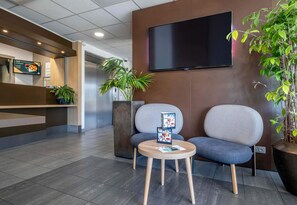Relax in comfort with a reception area featuring a digital screen, comfortable seating, and a large flat-screen TV.