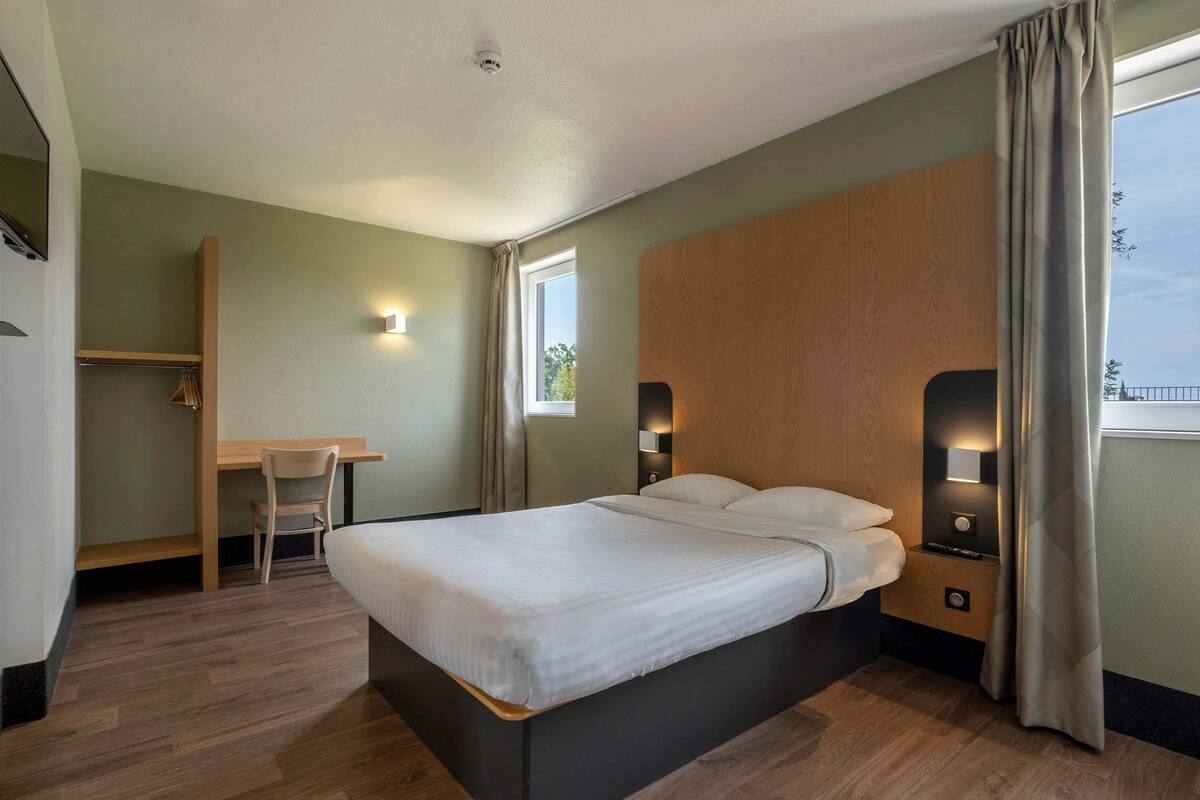 A hotel room with a bed, a desk, and a chair.