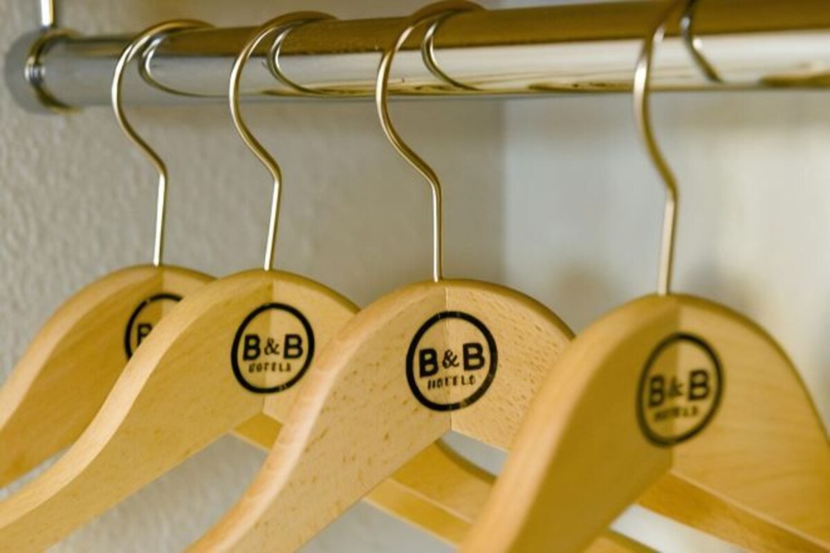 A row of wooden hangers with a logo on them, hanging on a metal rod.