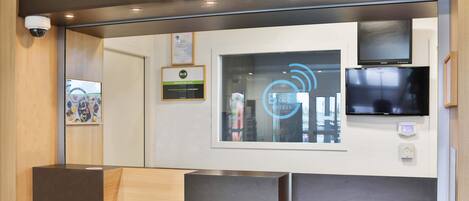 Un área de recepción de diseño moderno, con mostrador de recepción, televisor montado y un certificado enmarcado en la pared.
