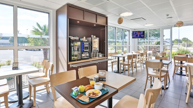 A breakfast area with tables, chairs, a refrigerator, and a television.