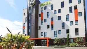 A modern hotel with a prominent "HOTEL" sign, a vertical entrance, and a logo for "B&B Hotels" on the facade.