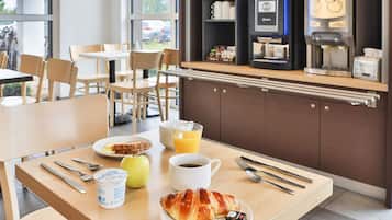 A breakfast setting with a croissant, juice, coffee, and yogurt on a table.