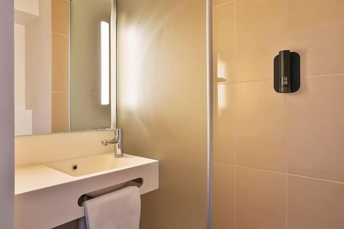 A modern bathroom with a white sink, a mirror, and a towel rack.