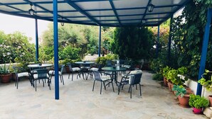 Un espace extérieur aménagé en terrasse, avec un sol en pierre et des tables et chaises en métal.