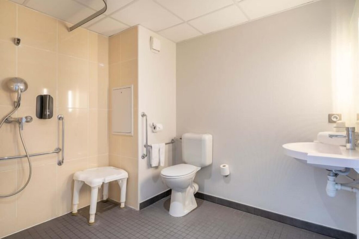 A modern bathroom with a shower, toilet, and sink.