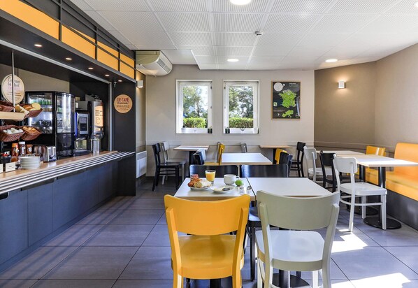 Una cafetería con mostrador, zona de estar y cartel con la carta.