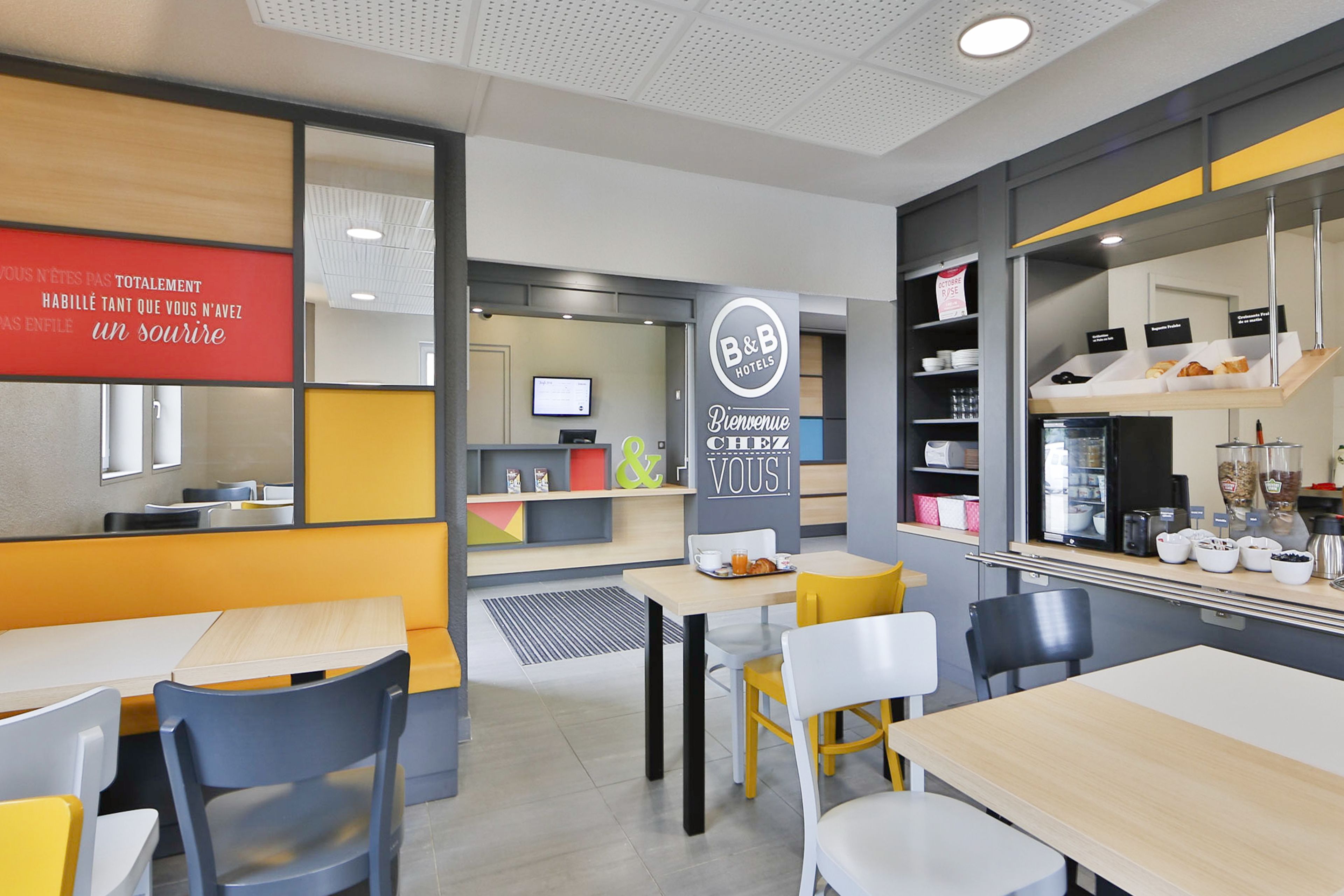 Un moderno vestíbulo de hotel con mostrador de recepción, zona de estar y mesa de buffet.