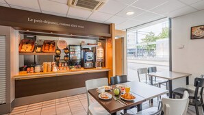 A breakfast counter with various food items and a coffee machine. There are tables and chairs for dining. - B&B HOTEL Mulhouse Centre (Mulhouse)