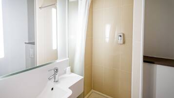 Un bagno con un lavandino bianco, una cabina doccia in vetro e uno specchio.