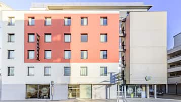 Un hôtel à plusieurs étages, doté d’une façade rouge et blanche, de nombreux balcons et d’un restaurant situé au rez-de-chaussée.
