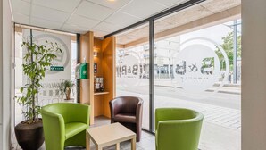 A modern interior with green chairs, a small table, and a potted plant. - B&B HOTEL Mulhouse Centre (Mulhouse)
