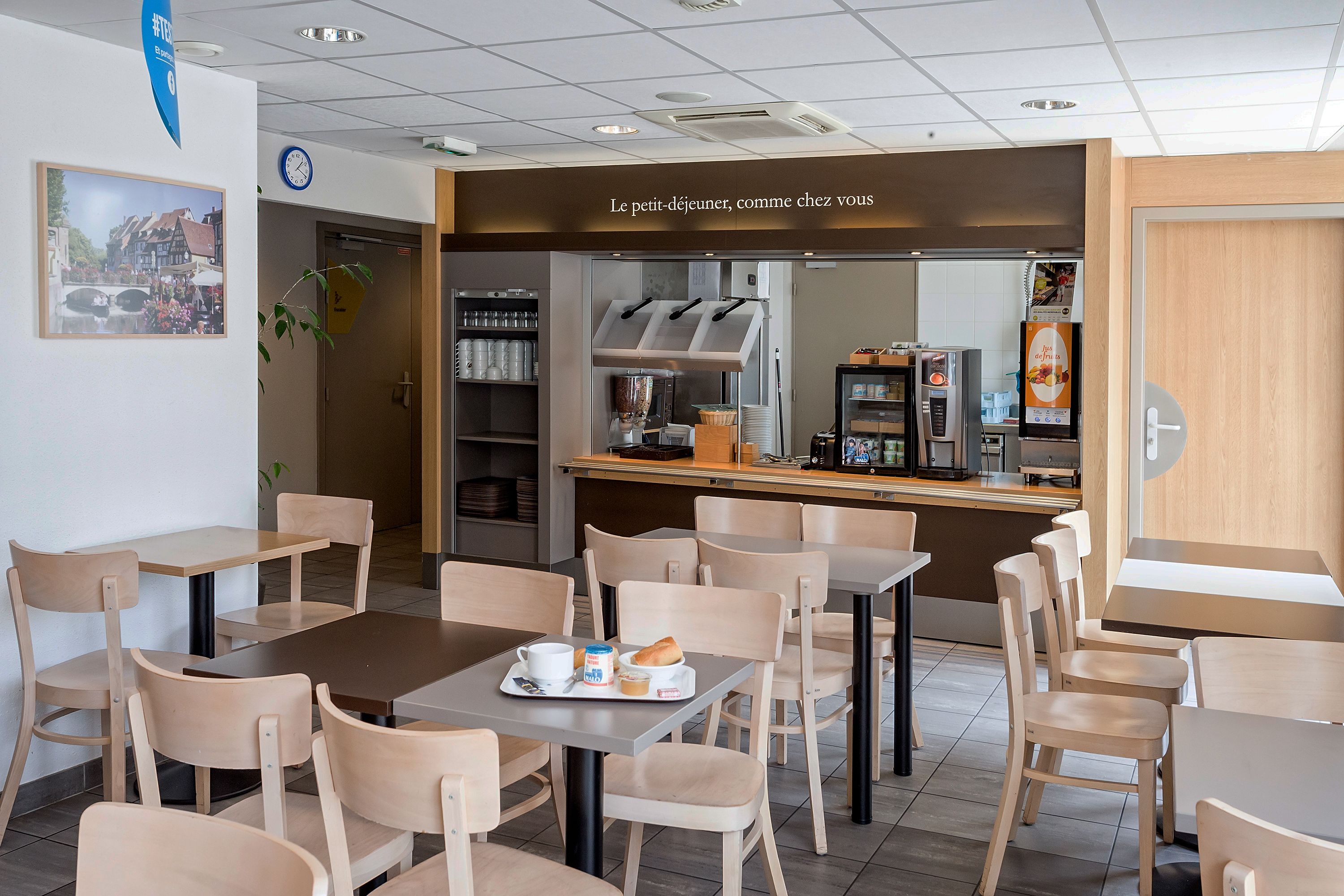 Un café avec des tables et des chaises, une horloge et un tableau affichant le menu.