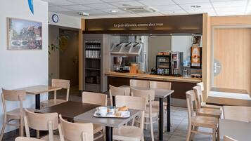 Un café avec des tables et des chaises, une horloge et un tableau affichant le menu.