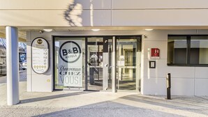 A hotel entrance with a glass door, a welcome sign, and a fire safety sign. - B&B HOTEL Mulhouse Centre (Mulhouse)