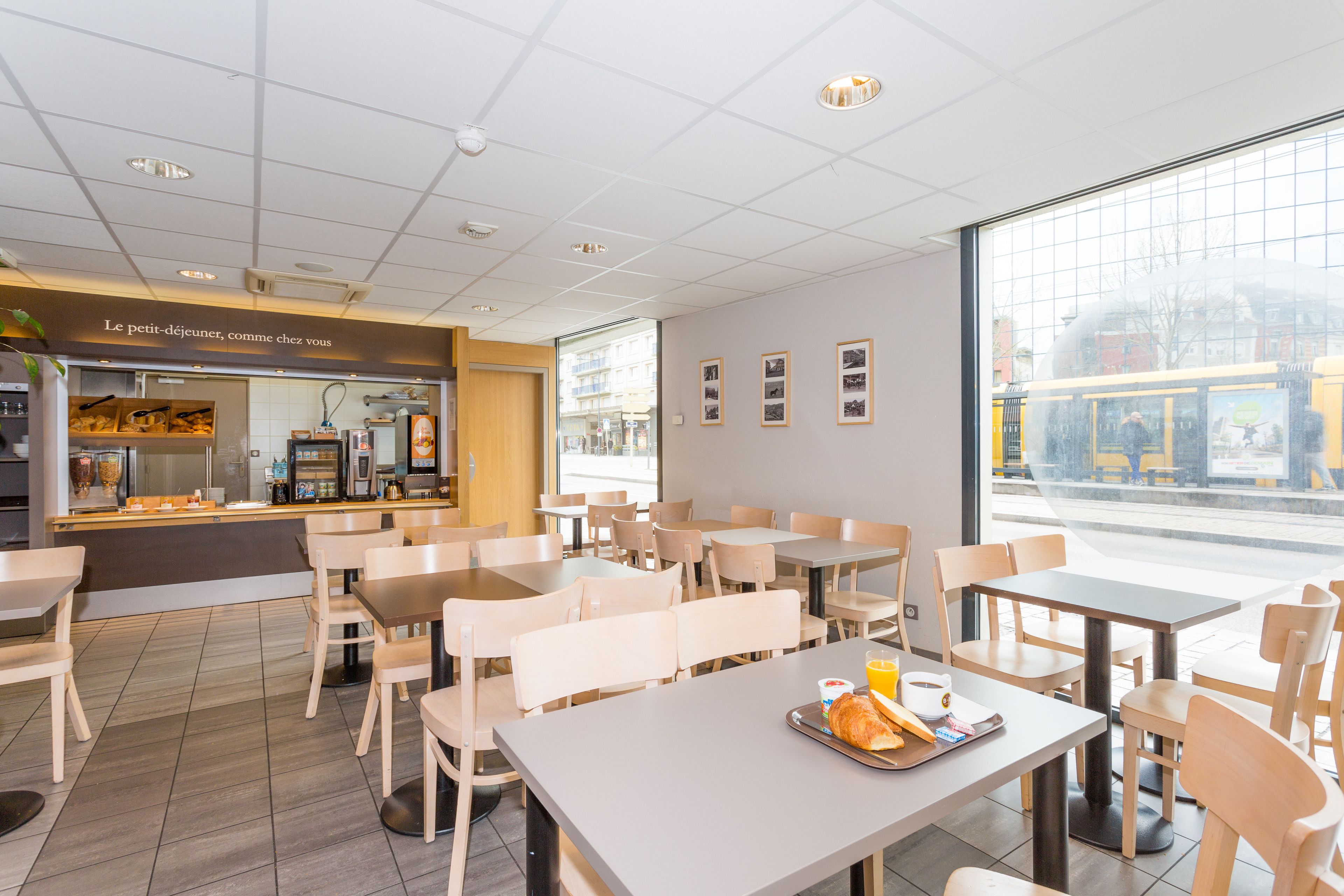 A café with tables and chairs, a counter with a menu, and a window with a view of the street.