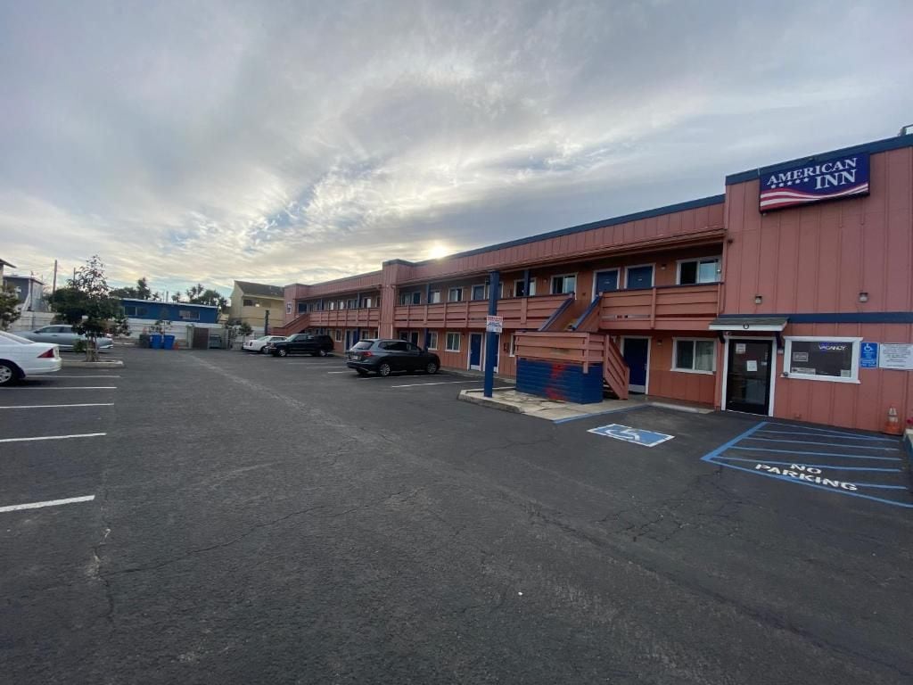 Un estacionamiento con un edificio que dice 'American Inn' al fondo.