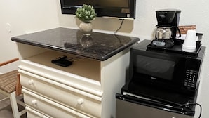 A kitchenette with a flat-screen TV, a coffee maker, a microwave, and a small refrigerator.