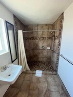 Un baño con ducha, lavamanos y espejo.
