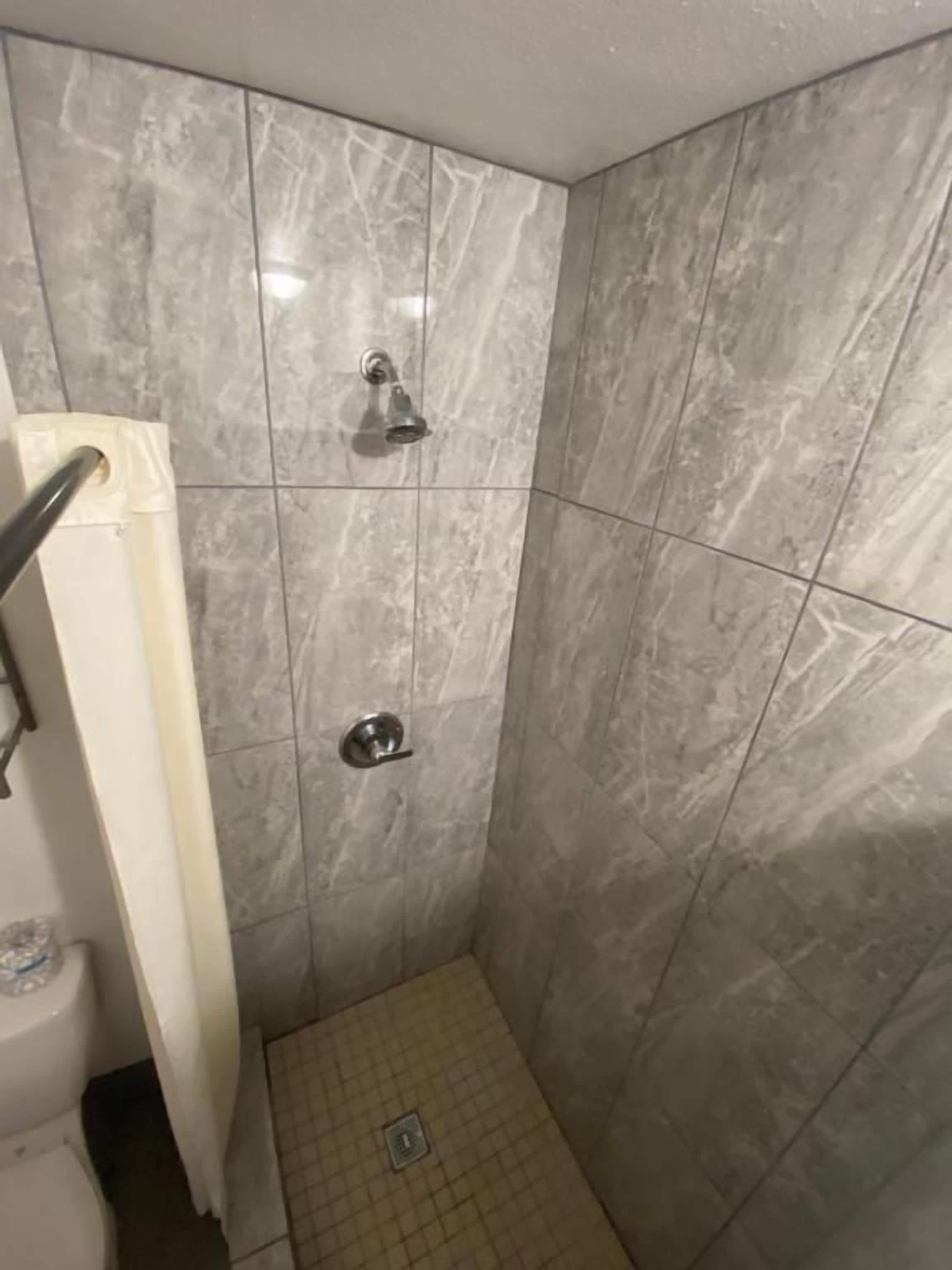 Een badkamer met een douchecabine, betegelde wanden en een toilet.