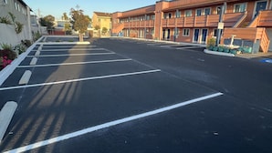 A parking lot with marked spaces and a building with multiple doors and windows.