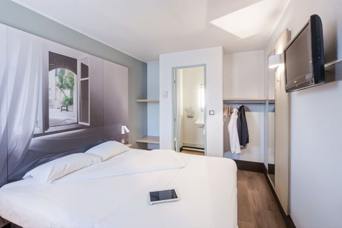 Un moderno cuarto de hotel con una cama grande, un televisor montado en la pared y vistas al exterior a través de una ventana.