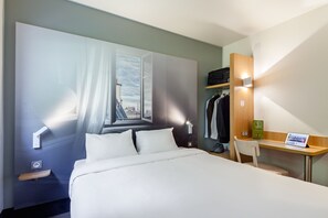 A hotel room with a bed, a desk, a chair, a wardrobe, and a wall-mounted TV. - B&B HOTEL Paris Nord Aulnay-sous-Bois (Aulnay-sous-Bois)