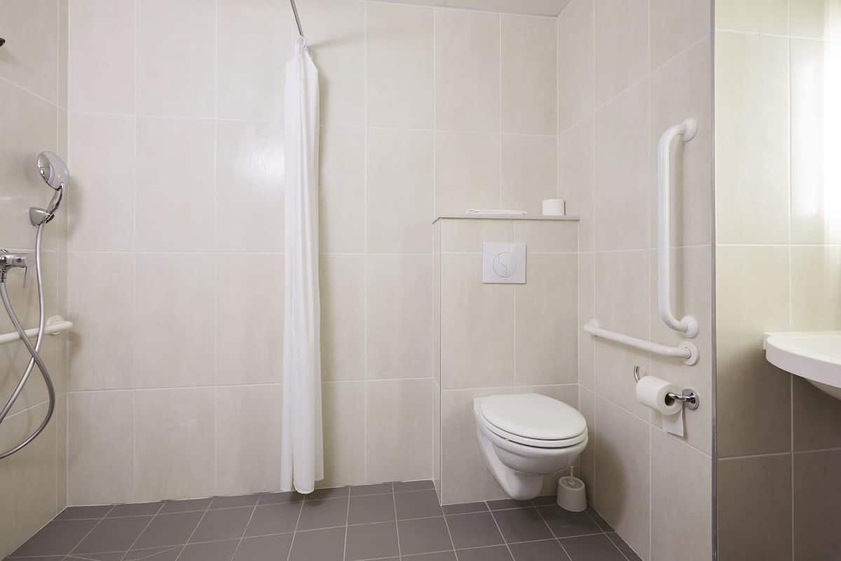 Une salle de bain équipée d’une douche, de toilettes et de barres d’appui.
