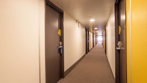 Un pasillo de hotel con puertas a ambos lados, piso alfombrado y una pared amarilla.