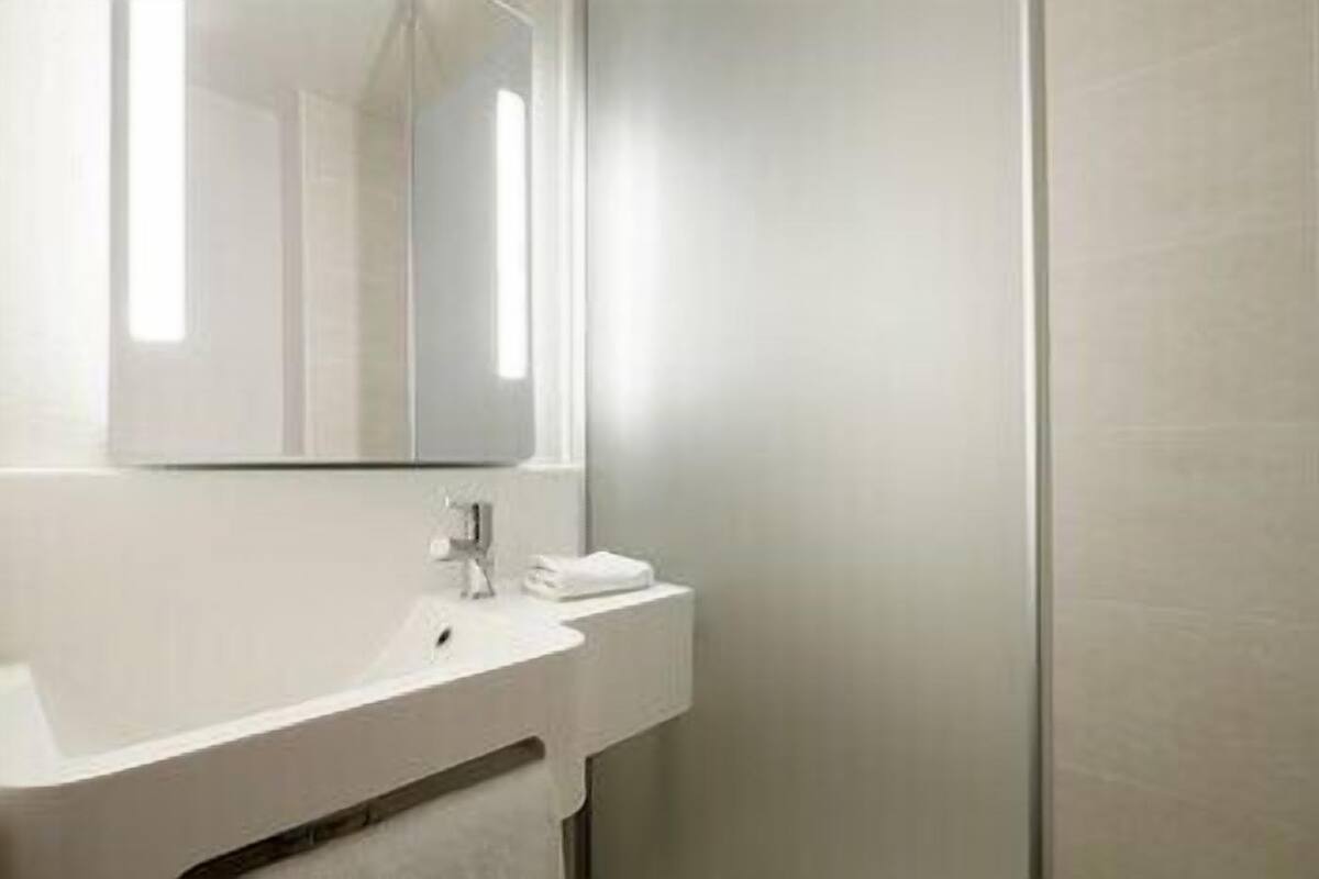 Une salle de bain avec un lavabo blanc, un miroir et une serviette.