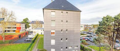 A multi-story residential building with a grey facade and a pitched roof.