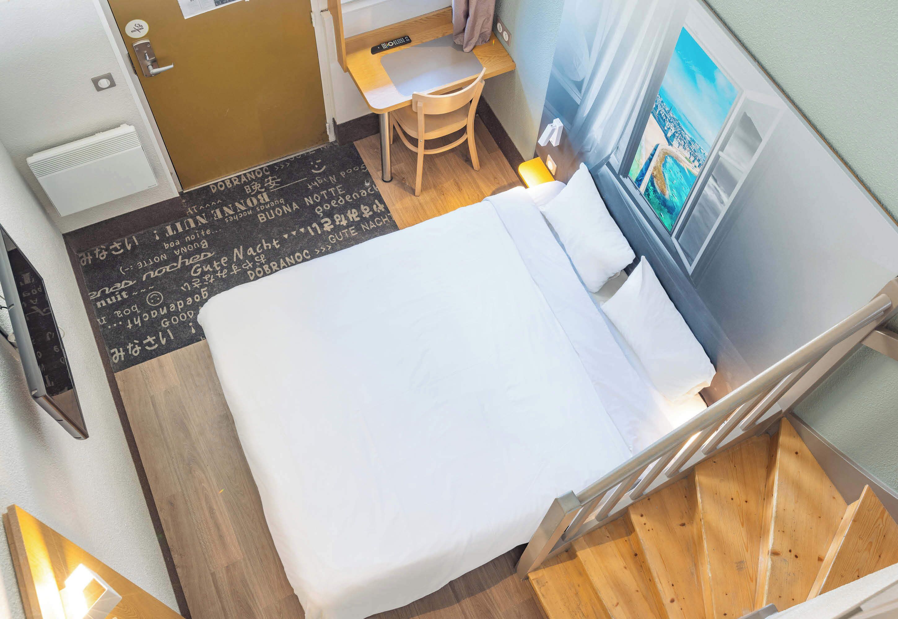Een hotelkamer met een bed, een bureau, een stoel en een raam met uitzicht.