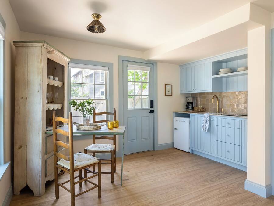 A kitchen with wooden cabinets, a dining table with chairs, and a small refrigerator.