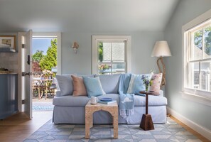 A cozy living room with a striped sofa, a small wooden table, and a lamp.